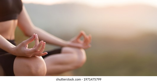 Close up with selective focus of hands woman sitting in yoga lotus pose outdoor at sunrise, meditating for balance. Horizontal banner view for website header design with copy space for text. 