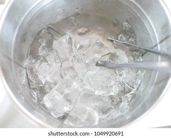 Close up and selective focus of ice in a bucket, with tongs, ready to be picked and put in any drinks - Shutterstock ID 1049920691