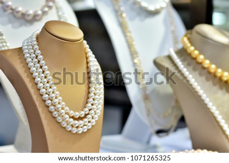 Close up and selective focus many pearl neckless show in a shop with blurred space and bokeh.