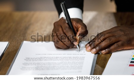 Close up and selective focus on African black formal professional business male hands holding pen, signing in white paper form or application to confirm and deal contract agreement on table
