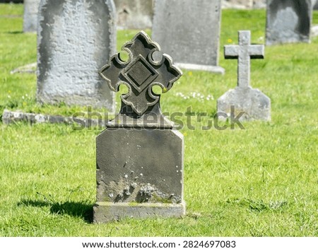 Close and selective focus on an ornate headstone in a cemetery, with soft bokeh and blurred background, emphasizing stone detail and a quiet, reflective atmosphere.