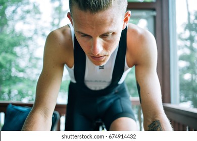 Close Up Selective Focus Photo Of Man Wearing Professional Cycling Bib Shorts And Base Layer Training On Cycling Roller Trainer Doing Hard Workout Inside His House