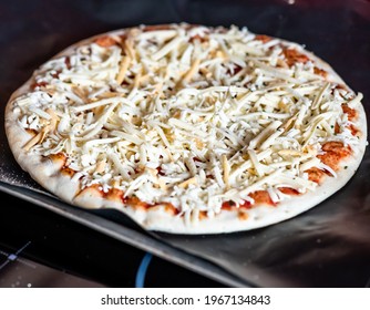 Close And Selective Focus Of A Readymade Frozen Stone Baked Thin Four Cheese Pizza On A Baking Mat Ready To Be Cooked In The Oven For Saturday Night Dinner