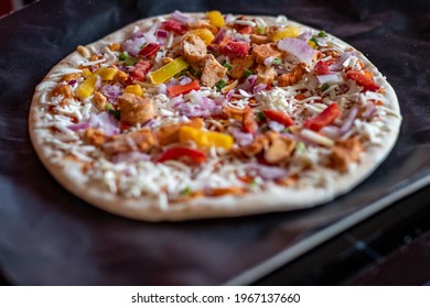 Close And Selective Focus Of A Readymade Frozen Stone Baked Thin Sweet Chilli Chicken Pizza On A Baking Mat Ready To Be Cooked In The Oven For Saturday Night Dinner