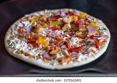 Close And Selective Focus Of A Readymade Frozen Stone Baked Thin Sweet Chilli Chicken Pizza On A Baking Mat Ready To Be Cooked In The Oven For Saturday Night Dinner