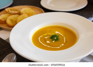 Close Up And Selective Focus Shot Of Pumpkin Soup With Vibrant Orange Color And Luxury Decoration In White Plate Shows Warm Dinner With Family In Thanksgiving Day Which Is Sharing Meal For Happiness.