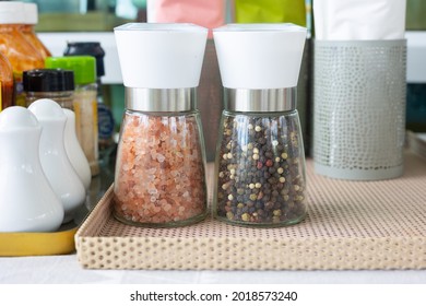 Close Up And Selective Focus Shot Of Two Bottle Of Pink Salt And Pepper In Containers With Grinder Prepared For Restaurant Customer And Placed In Spice Shelf. They Are Organic Ingredients For Meal.