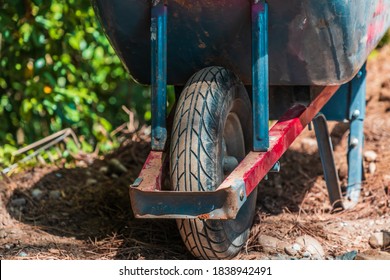 Close up selective focus shot of a wheelbarrow tire outside on dirt ground in a yard