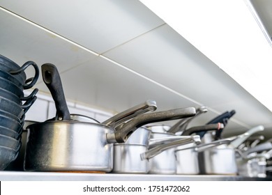 A close up selective focus view of pots and pans on a shelf in a restaurant kitchen