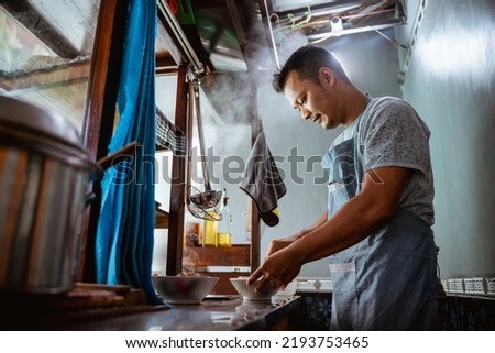 close up of seller prepares a serving of chicken noodles in a bowl on a cart