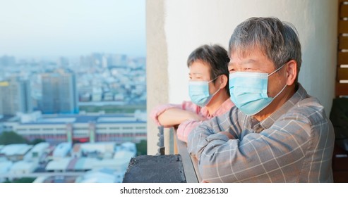 Close Up Of Senior Asian Couple Wearing Face Mask Looking Outside From Home