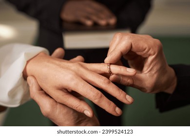 Close up of senior couple exchanging rings in church on wedding day, copy space - Powered by Shutterstock