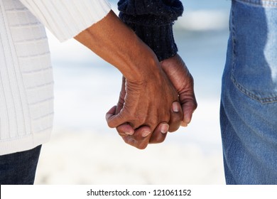 Close Up Of Senior Couple Holding Hands On Beach