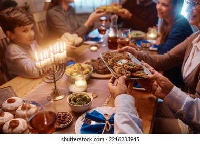 Close Up Of Senior Couple Passing Food During Family Dinner On Hanukkah.