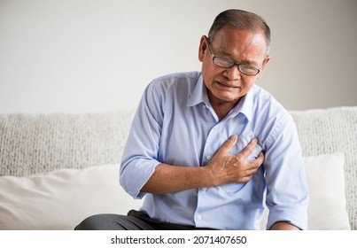 Close Up Senior Male Asian Suffering From Bad Pain In His Chest Heart Attack At Home. Healthcare And Medical Concept Of Senior Heart Disease.