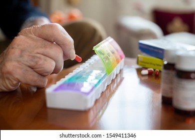 Close Up Of Senior Man Organizing Medication Into Pill Dispenser