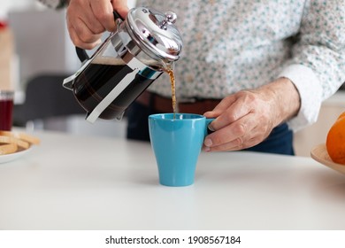 Close up of senior man pouring hot coffee from french press in kitchen during breakfast. Elderly person in the morning enjoying fresh brown cafe espresso cup caffeine from vintage mug, filter relax - Powered by Shutterstock