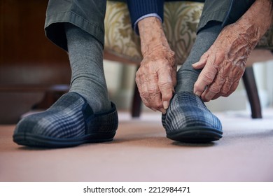 Close Up Of Senior Man Putting On Slippers To Keep Feet Warm In Cost Of Living Crisis