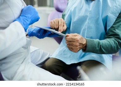 Close Up Of Senior Man Signing On Digital Tablet Dental Appointment At Dentist's Office.