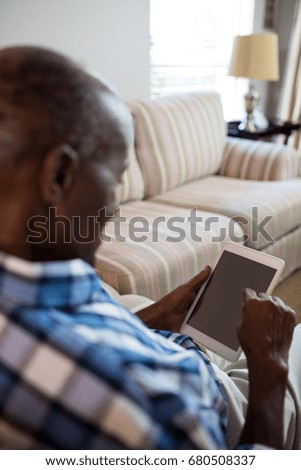 Close up of senior man using tablet while sitting on sofa at home
