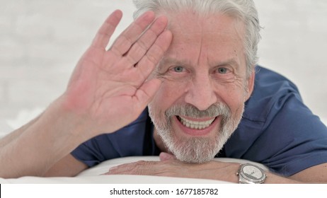 Close Up Of Senior Old Man Waving Hand While Lying In Bed