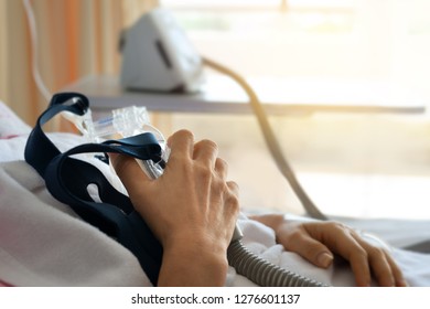 Close Up Of Senior Patient Woman Hand Holding Cpap Mask Between The Chest Lying  In Hospital Room.
Obstructive Sleep Apnea Therapy.