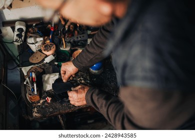 Close up of senior shoemaker hands gluing shoe sole at his workshop. Cropped picture of cobbler working at his workshop. A small business owner and craftsman is gluing sole at his cobbler small shop. - Powered by Shutterstock