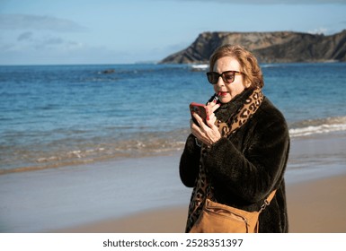 Close up of senior woman applying lipstick on a winter beach, using phone as a mirror,wearing a coat and sunglasses
 - Powered by Shutterstock