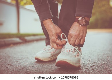 Close Up Of Senior Woman Hands Tying Sneakers.  