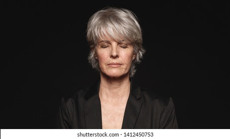 Close Up Of Senior Woman With Her Eyes Closed. Woman In Formal Wear Isolated On Black Background.