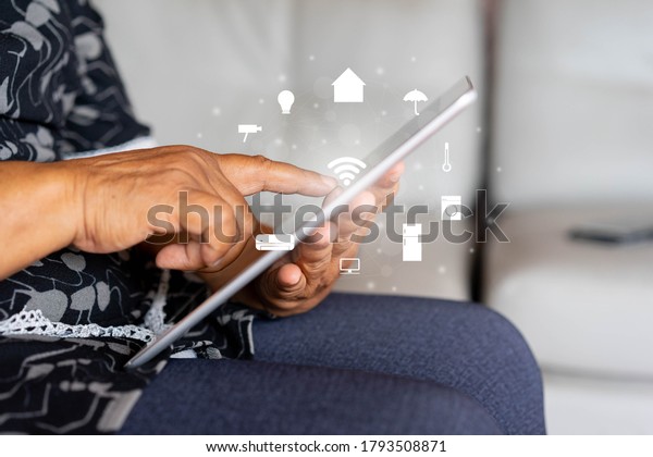 close up senior woman holding digital tablet and using\
wifi technology to home automation function for looking and monitor\
inside or outside home and property , mature life and ai innovation\
future 
