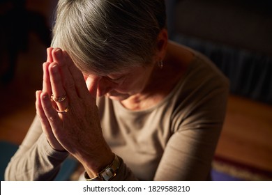 Close Up Of Senior Woman At Home Praying Or Meditating With Hands Together - Powered by Shutterstock