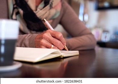 Close Up Of Senior Woman At Home Sitting At Table And Writing In Notebook Or Journal