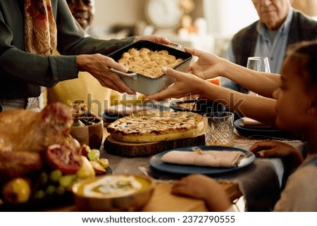 Close up of senior woman serving food to her family while celebrating Thanksgiving at home. 