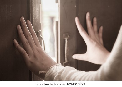 Close up sepia tone of women hand that is open door knob or push the door into outside from the temple, Beautiful old wooden door and sunshine in the morning for concept design or decorative