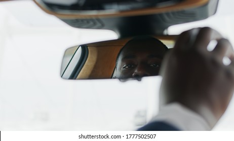 Close Up Serious African American Man Adjusting Rear View Mirror At Luxury Car. Focused Black Businessman Looking Into Rear View Mirror At Car. African Business Man Look At Car Mirror