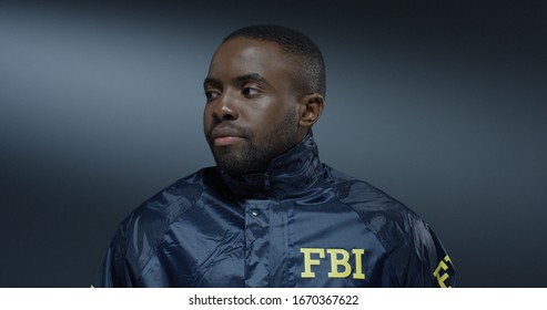 Close up of the serious African American young male FBI agent turning face to the camera and looking straight. Portrait.