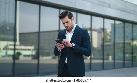Close up serious businessman reading bad news on phone at street. Disappointed man using smartphone outside. Young business man getting upset about news outdoors. - Shutterstock ID 1786685744