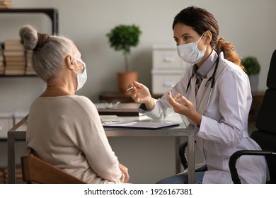Close up serious doctor wearing medical face mask consulting mature woman patient at appointment in office, physician explaining treatment, giving recommendations, elderly generation healthcare - Shutterstock ID 1926167381