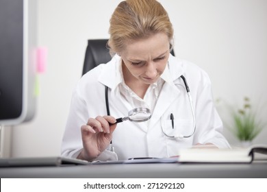 Close up Serious Female Doctor Reading at her Office Table Using a Magnifying Glass - Powered by Shutterstock