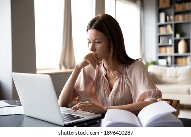 Close up serious focused woman looking at laptop screen, touching chin, sitting at desk, home office, thoughtful businesswoman pondering strategy, working on online project, searching information - Powered by Shutterstock