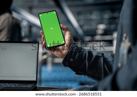 Close up of server farm software developer using mockup phone, waiting for code to finish compile. Data center employee checking mobile apps on green screen smartphone to relax