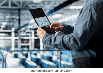 Close up of server room employee analyzing equipment metrics on device screen. Data center engineer looking at analysis charts on tablet from data gathered by infrastructure rigs