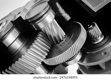 A close up of a set of gears with a black background. The gears are all different sizes and are all connected to each other. Concept of complexity and interdependence