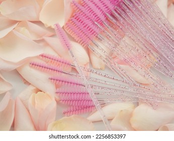 Close up of set of pink brushes for eyelash extensions or brows after treatment in beauty salon on background with petals of roses - Shutterstock ID 2256853397