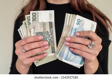 close up of several banknotes denomination of 100 zlotys Polish money zlotys holding a fan in the form of a woman in a suit. The concept of zlotys in women's hands