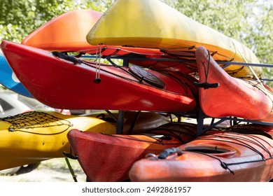 Close up of several colorful kayaks in stack on a beach. Kayak transportation and storage in sunny summer day. Red, orange and yellow boats in heap. Lifestyle, adventure expactation - Powered by Shutterstock