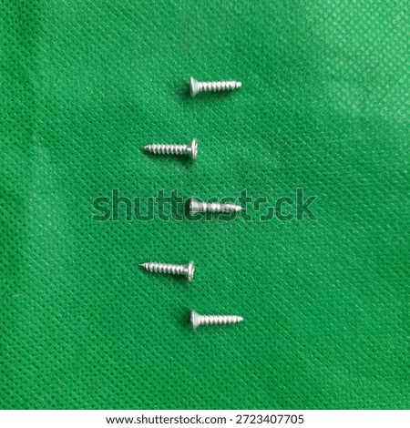 Close up of several medium sized taping screws against a green background