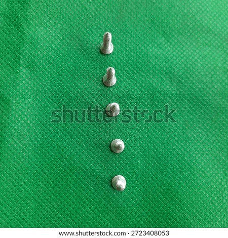 Close up of several medium sized taping screws against a green background