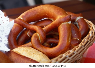Close up several traditional German pretzel bread knots and fresh buns in bread basket on table, high angle view - Shutterstock ID 2205594415